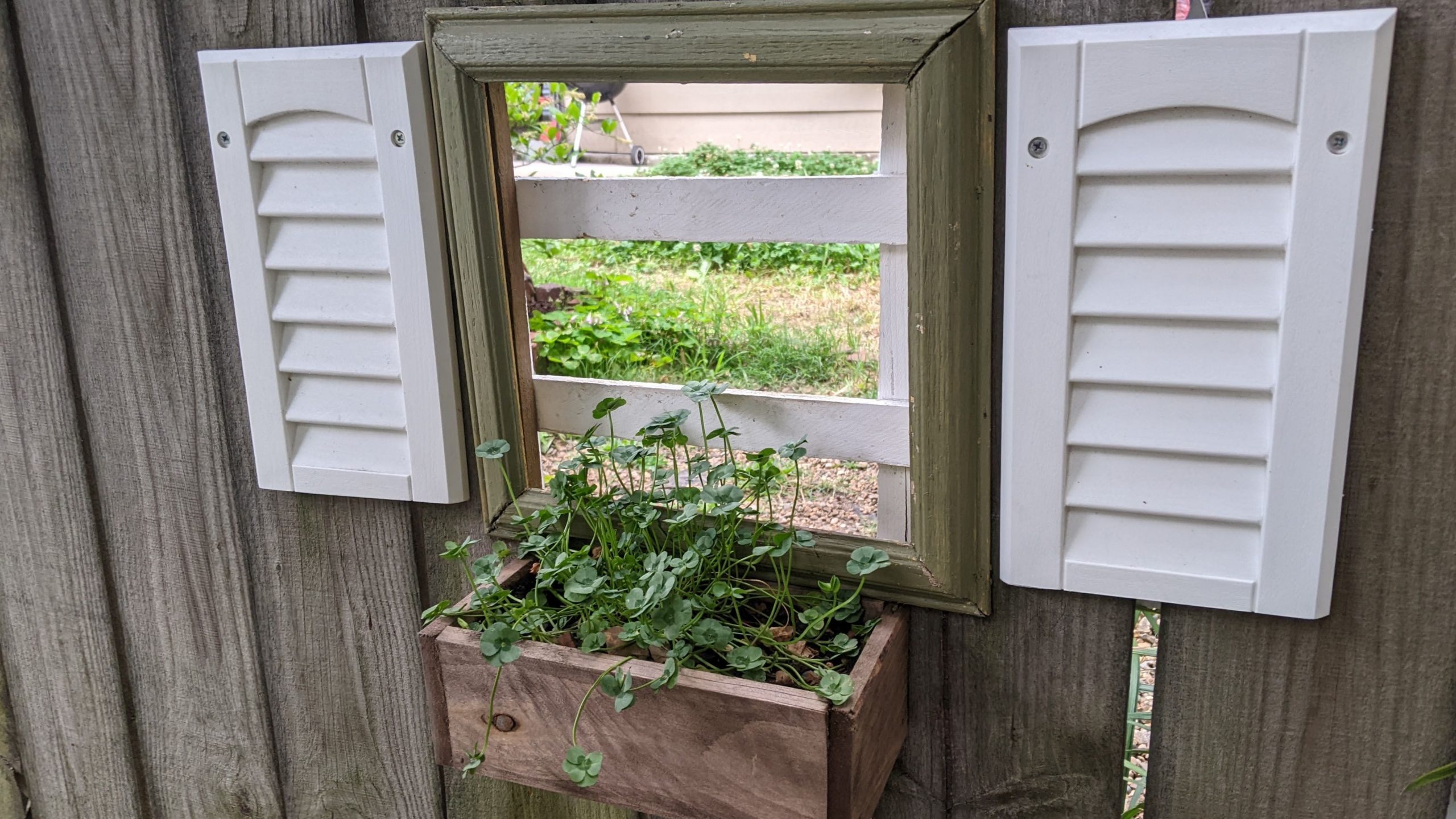 Picture frame, shutters, and window box framing a hole in a fence at the Cooper-Young Garden Walk
